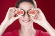 A mid adult woman holding figs up to her eyes