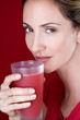 A mid adult woman drinking a glass of fruit juice