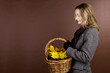A woman holding a basket of conkers, acorns and autumn leaves