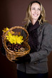 A woman holding a basket of conkers, acorns and autumn leaves