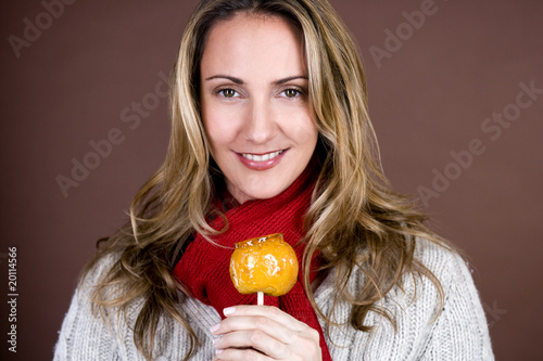 Photo: A mid adult woman holding a toffee apple, smiling A mid adult woman holding a toffee apple, smiling