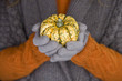 A woman holding a small pumpkin, close-up