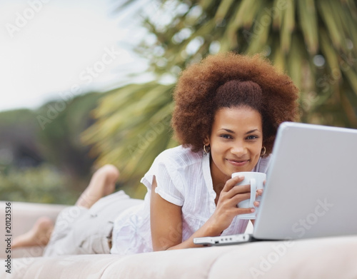 Photo: Black girl with a laptop and coffee while on couch outdoors Black girl with a laptop and coffee while on couch outdoors