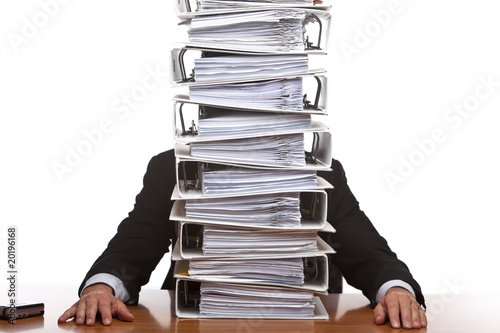 Foto: Frustrated Business man in office with huge paperwork (folders) Frustrated Business man in office with huge paperwork (folders)