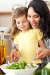 Brunette mother helping her daughter prepare salad