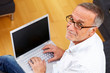 Images : mature man with laptop and reading specs looking to camera
