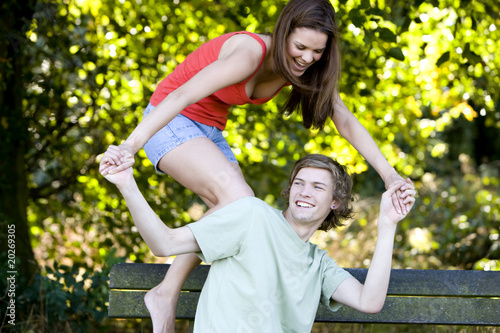 Photo: A young couple having fun on a park bench A young couple having fun on a park bench
