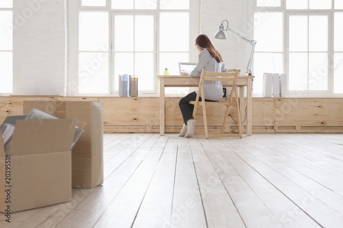Foto: Woman sits at desk in window area of loft apartment Woman sits at desk in window area of loft apartment