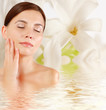 Beautiful young woman with sprig flower reflected in water