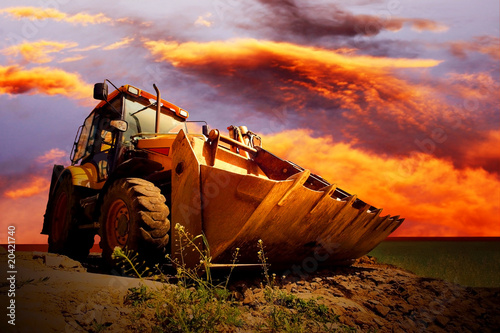 Photo: Yellow tractor on golden surise sky Yellow tractor on golden surise sky