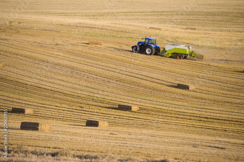 Photo: Tractor and straw baler in wheat field Tractor and straw baler in wheat field