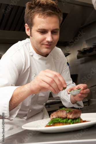 Foto: Chef Adding Seasoning To Dish In Restaurant Kitchen Chef Adding Seasoning To Dish In Restaurant Kitchen