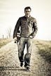 musician with guitar walking along the road