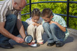 father is using magnifier to burning paper. children is looking