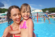 Smiling beautiful woman and little girl bathing in pool