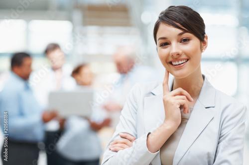 Foto: Smiling cute business woman with colleagues at the back Smiling cute business woman with colleagues at the back