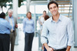 Smiling young man with his colleagues at the back