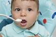 Baby boy in high chair with spoon at his mouth