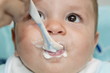 Closeup of baby boy's face with with spoon and food around his mouth