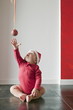 Baby boy sitting on floor reaching for Christmas ball