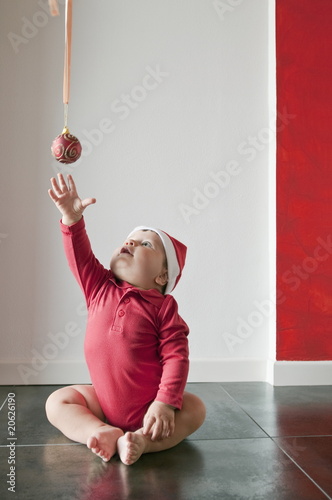 Photo: Baby boy sitting on floor reaching for Christmas ball Baby boy sitting on floor reaching for Christmas ball