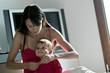 Young woman dressing baby boy