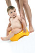 Baby boy on potty being held by young woman's hands