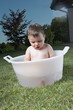 Baby boy taking bath in tub in garden