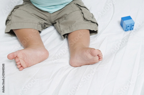 Photo: Closeup of baby's feet with block toy Closeup of baby's feet with block toy