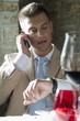 Young man in suit with mobile phone at a restaurant checking time