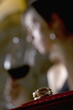 Closeup of ring with young woman in the background drinking red wine