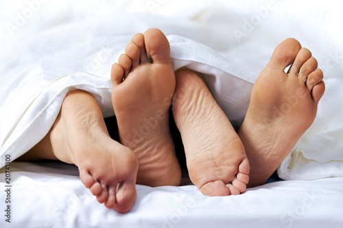 Photo: Close-up of the feet of a couple on the bed Close-up of the feet of a couple on the bed