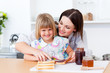 Smiling little girl and her mother preparing toasts