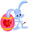 Cute bunny lying on his painted Easter egg holding a paintbrush
