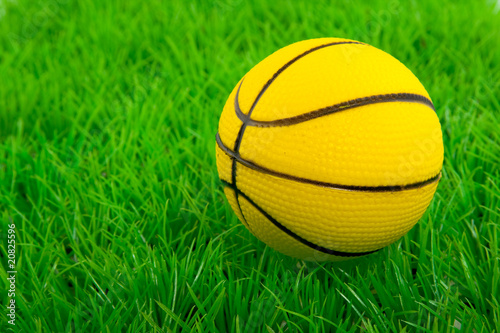 Photo: a yellow basketball on a green plastic lawn a yellow basketball on a green plastic lawn