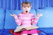 surprised little girl with apple and books in sofa