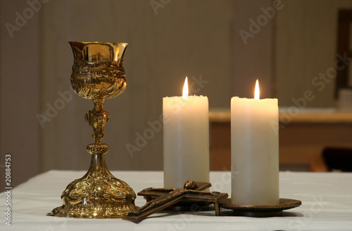 Photo: Golden chalice and two burning candles Golden chalice and two burning candles