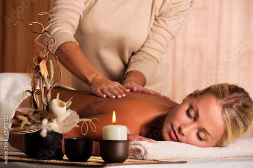 Photo: masseur doing massaging back of a beautiful young woman masseur doing massaging back of a beautiful young woman