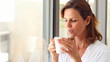 Mature woman blowing cool air in her cup of coffee