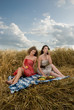 Two beautiful slavonic girls on picnic in wheat field