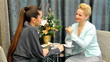 Women talk at a table in cafe. Mother gives jewllery as present