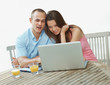 Happy young couple browsing the internet on a laptop