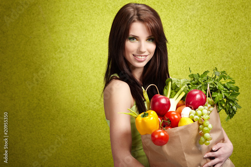 Portrait of a girl holding in hands full of different fruits and
