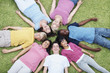 Happy teenagers lying on grass head to head