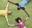 Top view of happy young three friends lying on grass