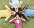 Four shouting multi ethnic teens lying on grass head to head