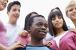 Smiling teens standing with focus on an African American boy