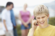 Closeup of boy talking on cellphone with friends in background
