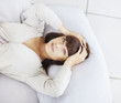Cute woman lying on a pillow and holding head in tension