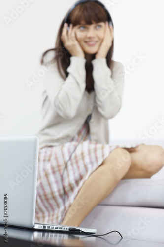 Photo: Female at the background listening to music over a laptop Female at the background listening to music over a laptop